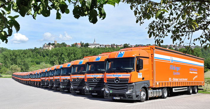 Ein riesiger LKW für Maschinentransporte steht dekorativ vor dem Eingang des Neubaus der Rüdinger-Spedition. Im Hintergrund Krautheim und die Burg Krautheim. Das Laub ist herbstlich, der Himmel blau.
