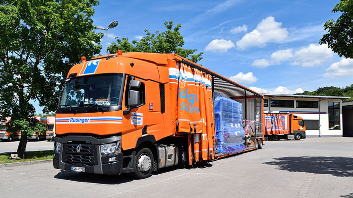 Es ist ein künstlerisches Foto, dem Fotografen gefiel eine neue Zugmaschine für einen Maschinentransport vor dem neuen Verwaltungsgebäude der Rüdinger Spedition. Zwischen LKW und Haus ist ein Baum.