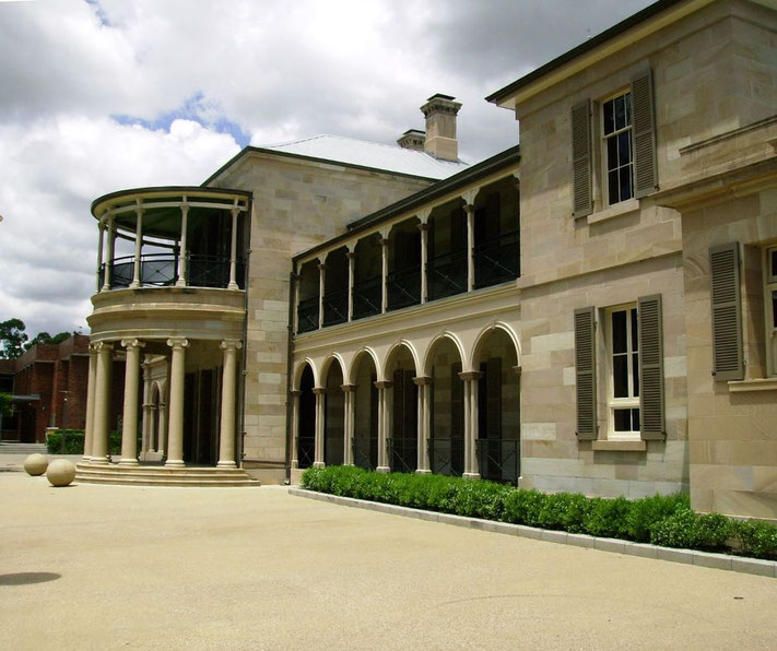 Old Government House in Brisbane, Australia. Built in the 19th century, it features sandstone walls, arched verandas, and classical columns.