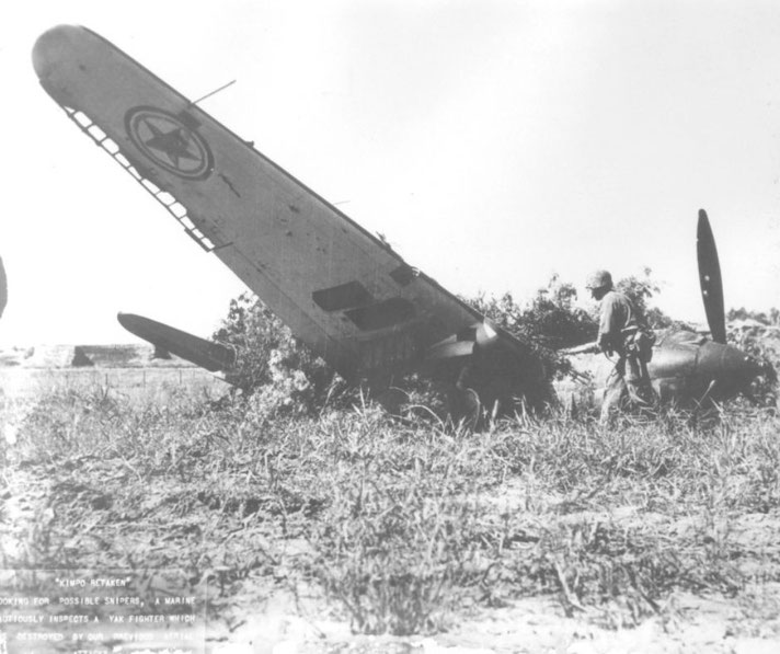 Looking for possible snipers, a Marine cautiously inspects a Yak fighter which was destroyed by previous aerial attacks during the Korean War battle in which Kimpo was retaken.