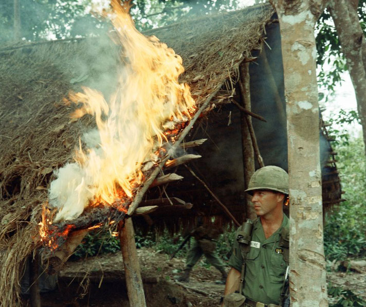 During Operation “Crimp” near Bien Hoa, RVN, the 28th Infantry, 1st Infantry Division found a Viet Cong village while on a search and destroy mission SGT Richard McConchie watches a fire he started.