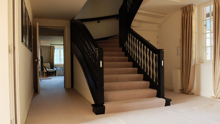 Escalier monumental Villa Lalique en laque noire, les marches sont habillées de moquette rose clair