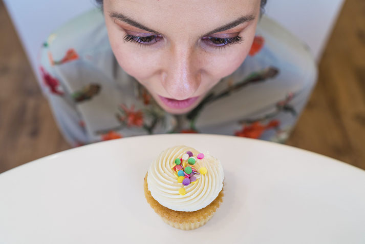 Eine Frau schaut gierig auf ein Zuckertörtchen.