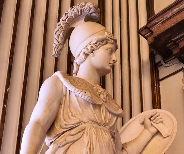 Marble statue of a warrior woman in a plumed helmet, holding a round shield, with a Medusa head on her chest.