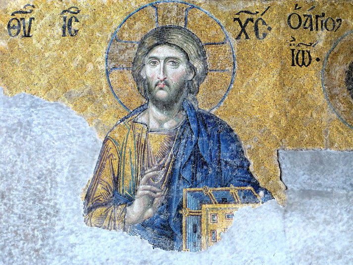 Ancient mosaic of Christ with a halo and hand raised in blessing, set against a golden background with Greek text.