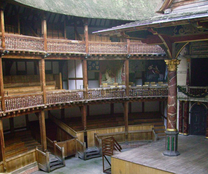 A reconstructed Elizabethan theater with wooden balconies, tiered seating, and an open central stage, resembling the iconic design of Shakespeare's Globe Theatre.