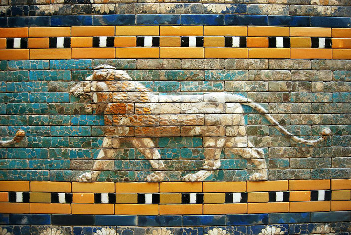 A lion relief made of glazed bricks features on a colorful ancient wall with turquoise, gold, and black accents.