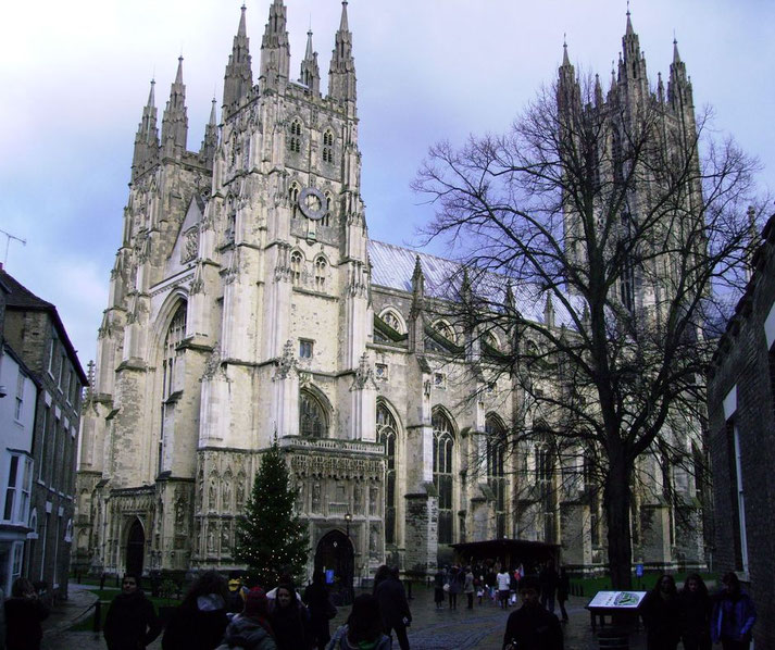 A grand Gothic cathedral with towering spires and intricate stonework stands against a cloudy sky.
