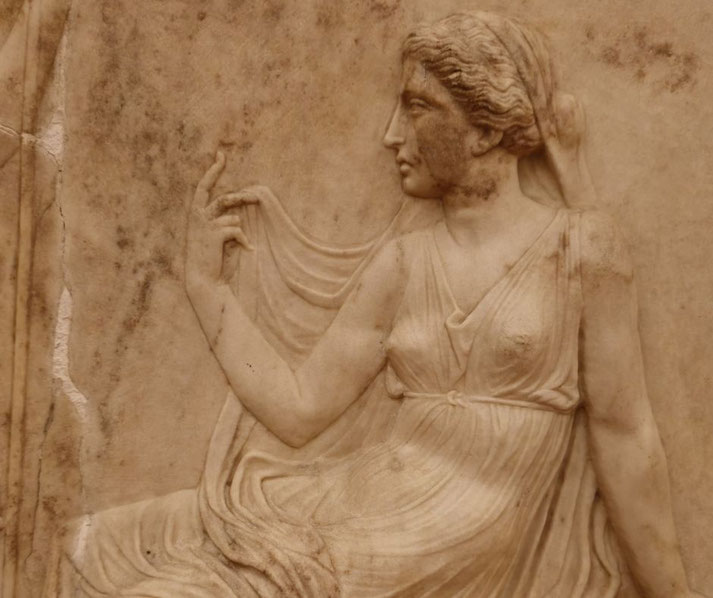Marble relief of a woman in flowing drapery, seated in profile, with one hand raised in a graceful gesture, hair tied and partially covered.