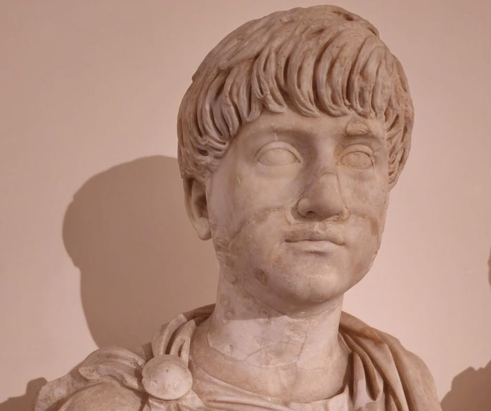Marble bust of a young man with short, textured hair and a calm expression, dressed in a classical toga with a decorative clasp.
