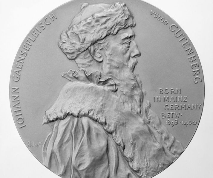 A a commemorative medal featuring a relief portrait of Johannes Gutenberg, the inventor of the printing press.