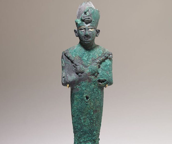Bronze statuette of Osiris with Ramesside-style features, missing beard, and traces of inlays in eyes, brows, and scepters.