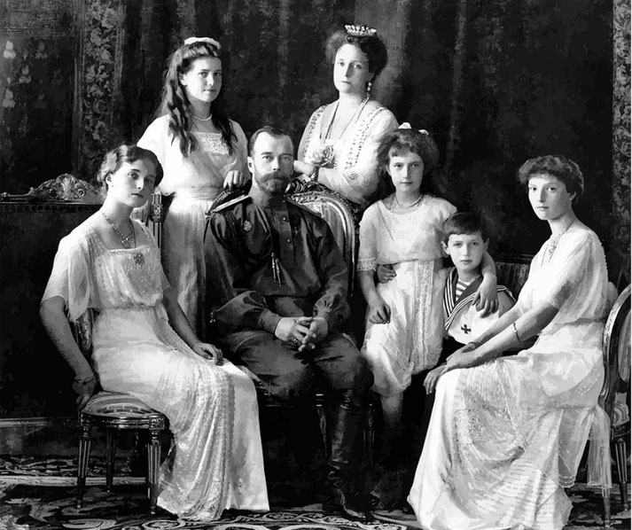 Black and white portrait of a royal family, with a man in military uniform seated at the center, surrounded by six women and one boy in formal attire.