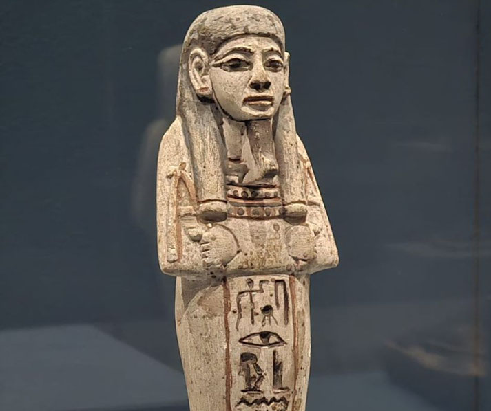 An ancient Egyptian shabti figurine, a small funerary statue inscribed with hieroglyphs. These figures were placed in tombs to serve the deceased in the afterlife, performing tasks on their behalf.
