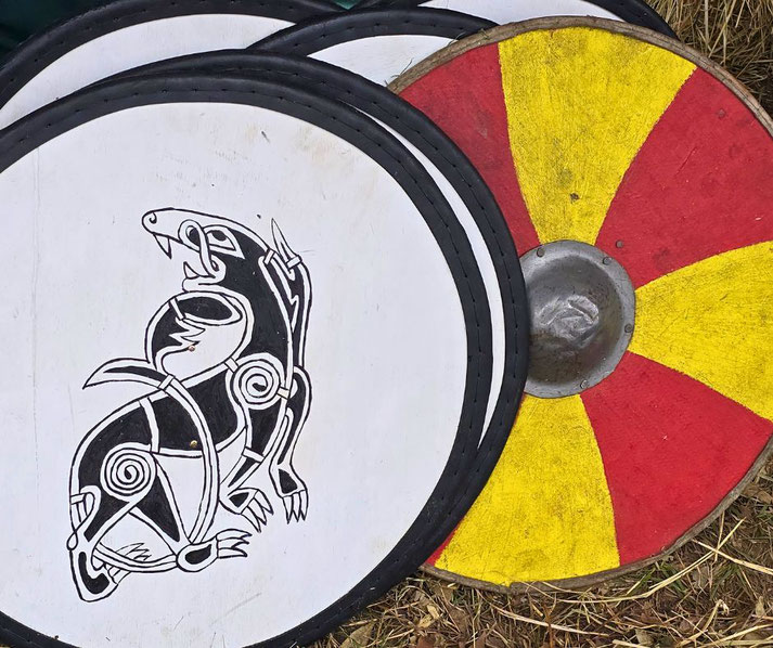 Two Viking shields are displayed: one with a black and white wolf design, and the other with a red and yellow divided pattern.