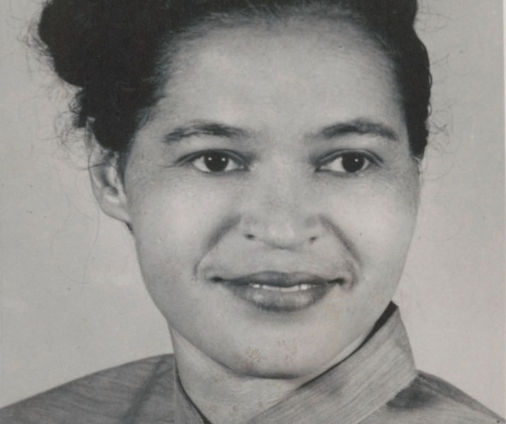 Black-and-white portrait of a woman with hair tied back, wearing a high-collared garment, looking slightly to the side with a composed expression.