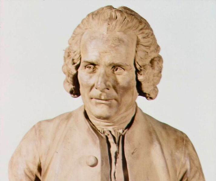 A classical bust sculpture of a man with wavy, shoulder-length hair. He has a calm yet serious expression and wears a buttoned coat with a high collar.