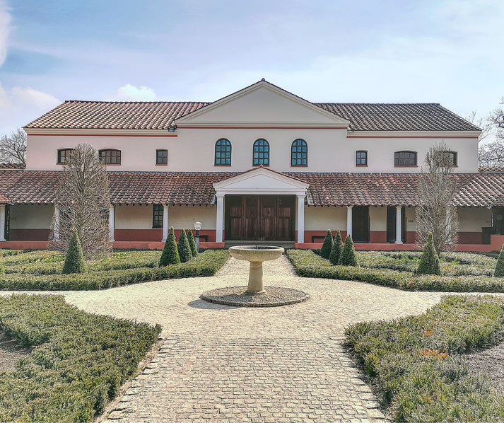 A reconstructed Roman villa with a symmetrical design, red-tiled roof, and classical columns.