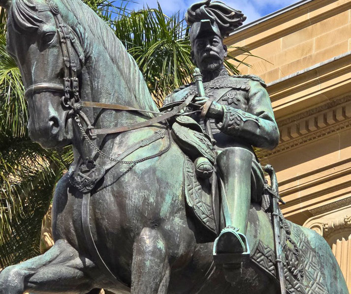 A bronze equestrian statue of a regal military figure features intricate details, including a feathered hat, medals, and ornate attire. 