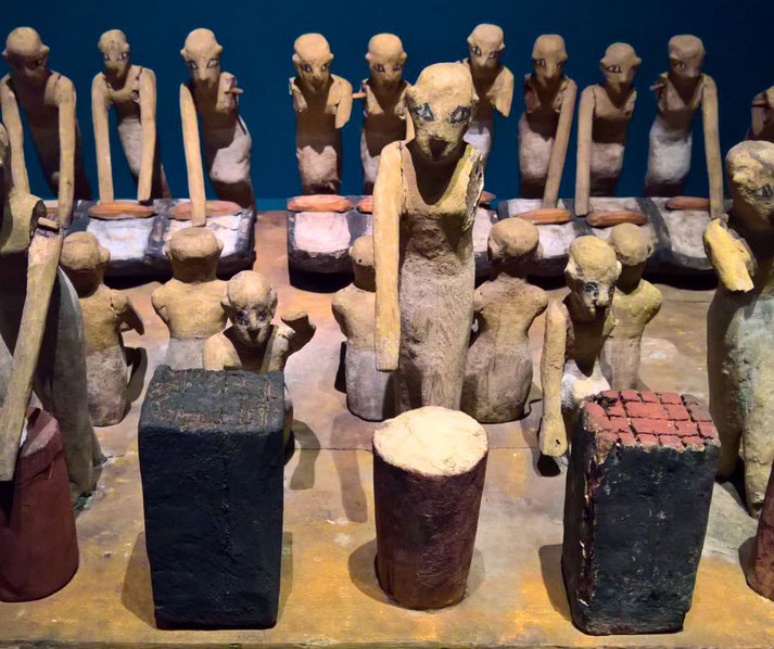 An ancient Egyptian wooden model of workers engaged in food preparation. These figurines were placed in tombs to provide for the deceased in the afterlife, depicting daily life activities.