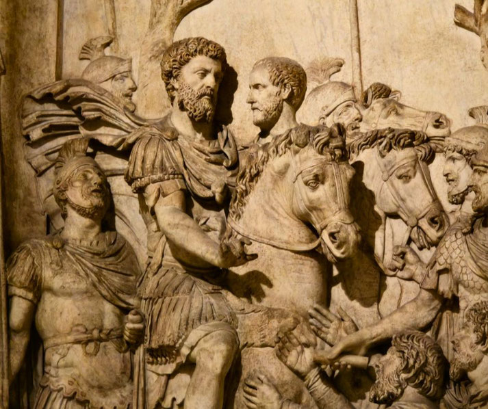 Intricate stone relief of Roman soldiers on horseback in a battle or victory scene, with detailed armor, horses, and expressive gestures.