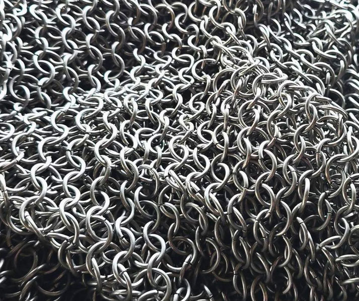 A close-up of chainmail armor, showing interlocking metal rings in a dense, protective weave. 