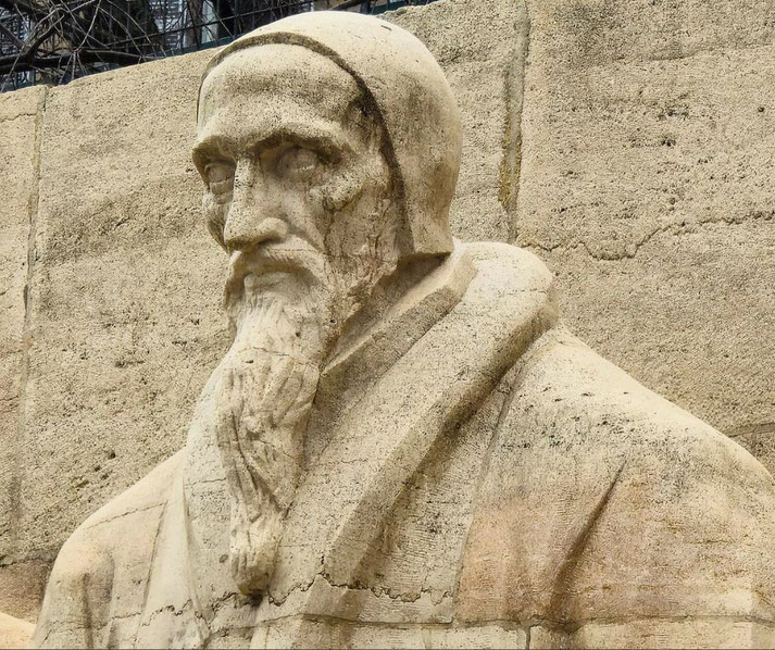 A close-up of a stone statue of John Calvin in Geneva, Switzerland. His stern expression and detailed carving reflect his influence as a key figure in the Protestant Reformation.
