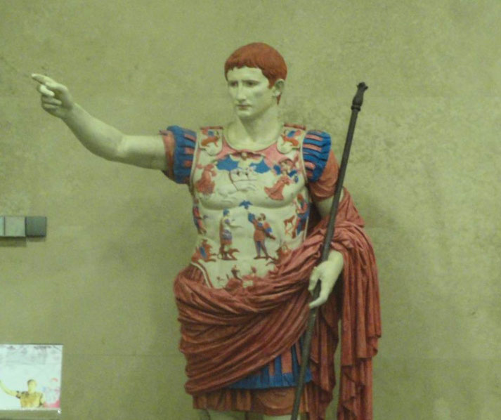Painted Roman statue of a man in detailed armor, holding a staff and pointing forward with a commanding pose.