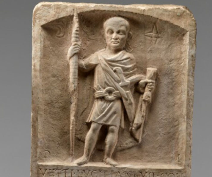A Roman soldier stands beside a bound prisoner before an emperor, depicted in a relief-style composition.