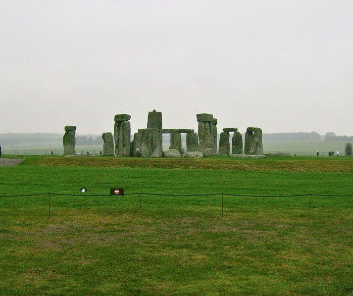 Stonehenge stands on a grassy plain under an overcast sky, its massive stones arranged in a circular formation.