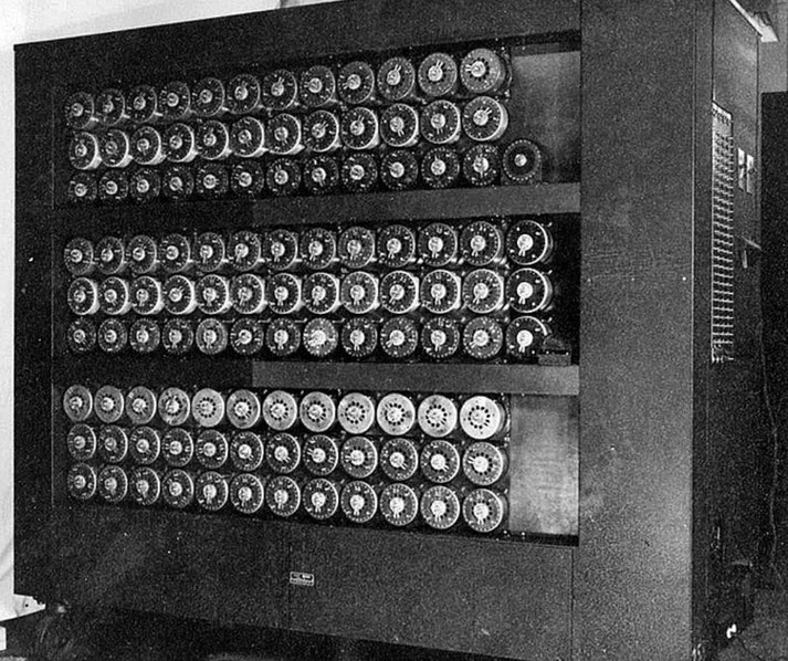 Black-and-white image of a Bombe machine used during WWII for decrypting coded messages with rows of rotating drums.