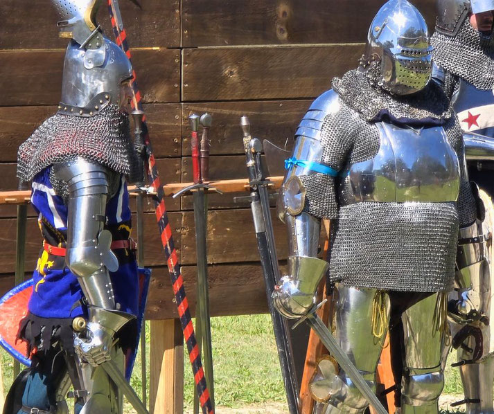 Two armored knights in full plate and chainmail at a medieval reenactment.