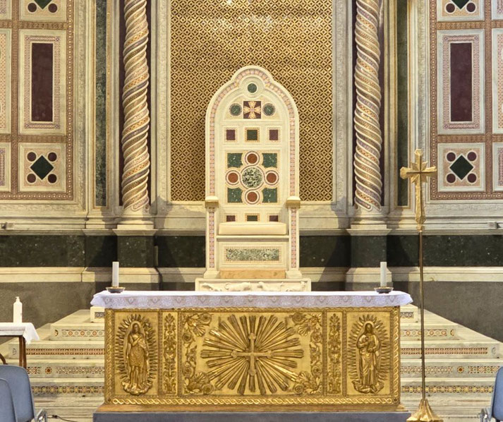A marble papal throne behind a gold altar featuring religious carvings, flanked by twisted columns and intricate patterned walls.