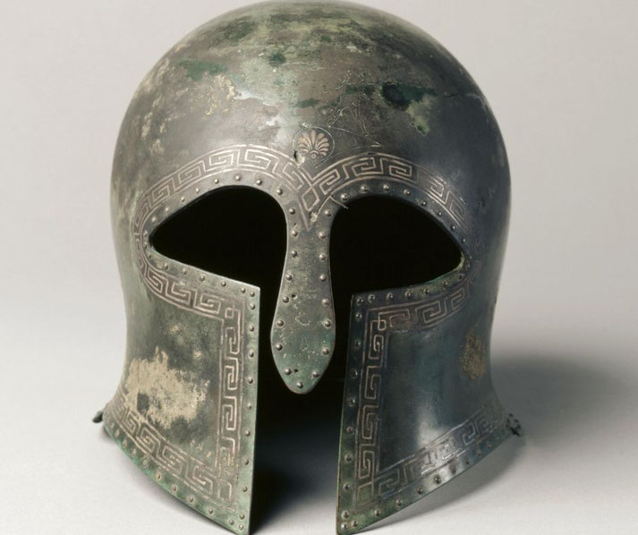 Bronze Greek helmet with silver inlay, featuring almond-shaped eye holes, large cheek-pieces, and a wide nose-guard.