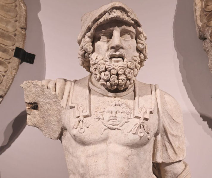 Marble statue of a bearded warrior wearing a decorated breastplate with a Medusa head; the left arm is missing and the right is partially broken.