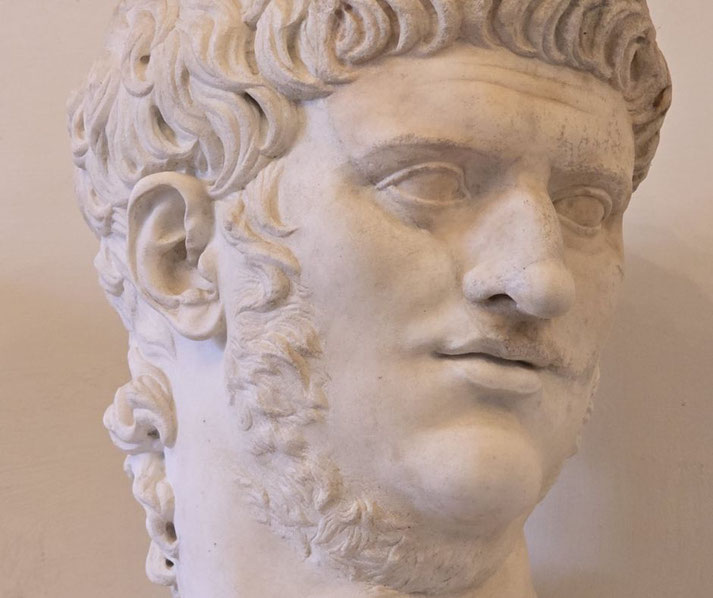 Marble bust of a man with thick, curled hair, sideburns, and a faint mustache, featuring a prominent nose and intense expression.