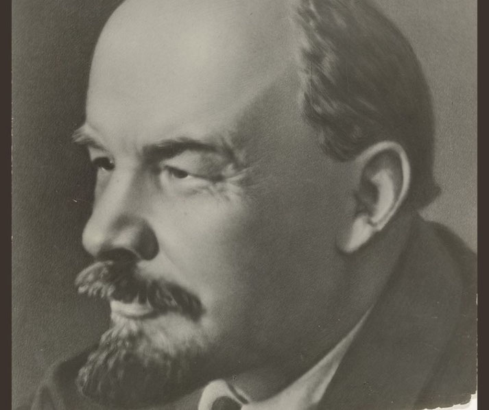 Black and white close-up portrait of a bald man with a mustache and goatee, gazing to the left.