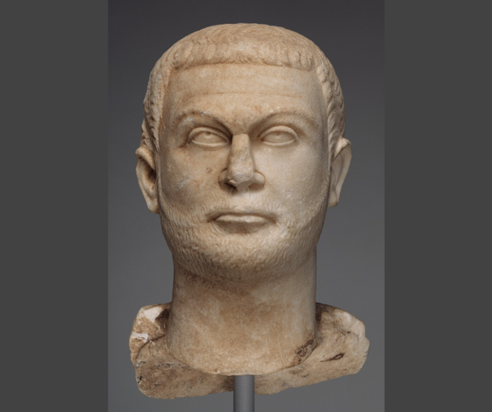 Marble fragment depicting Roman Emperor Diocletian in a toga, showcasing detailed drapery and imperial attire.