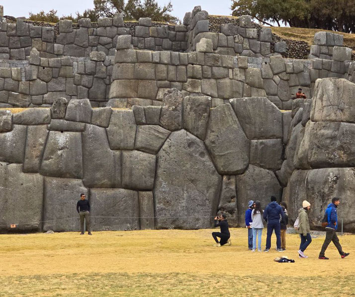An ancient Incan fortress near Cusco, Peru. The site features massive, precisely cut stone walls, with visitors exploring the area.