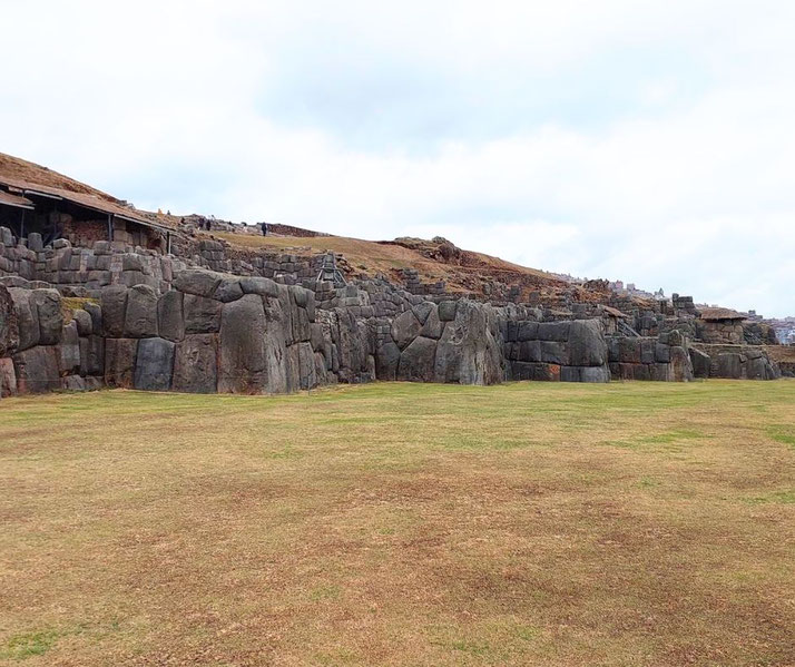A view of Sacsayhuamán, an ancient Inca fortress in Peru, featuring massive precisely-cut stone walls and terraces.
