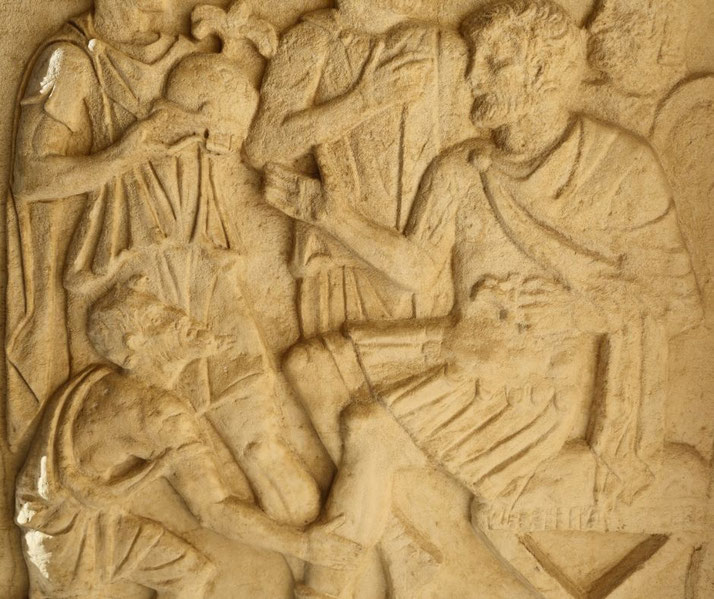 Stone relief showing a bearded man seated among others in togas, with a kneeling figure below.