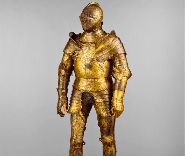 A full suit of ornate, gilded armor with intricate engravings, featuring a closed helmet and articulated joints.