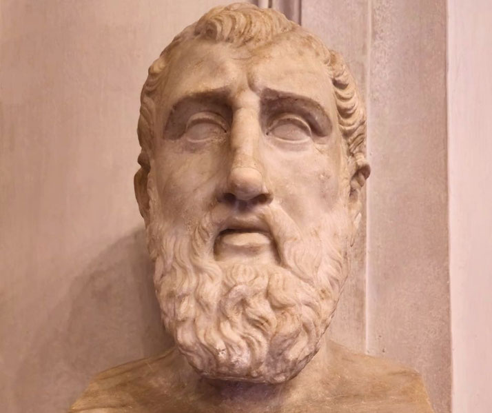 Marble bust of a bearded man with a solemn expression, featuring deep-set eyes and short, wavy hair.