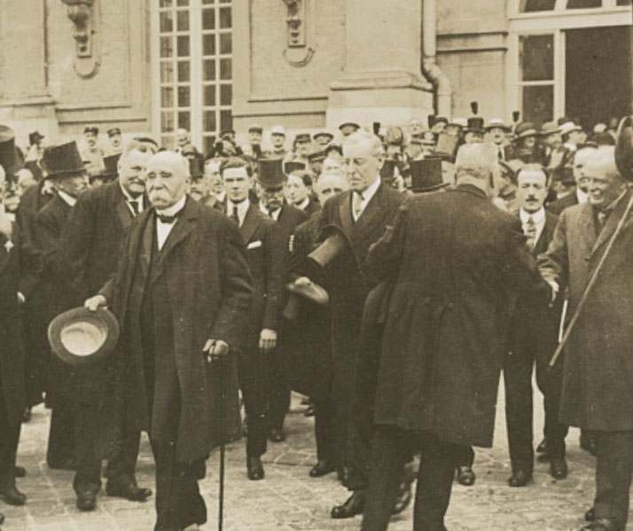 Historic photo of political leaders and diplomats in formal attire gathered outside a grand building, likely after a major event.