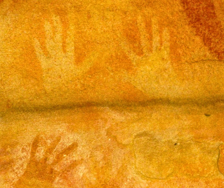 Ancient Indigenous Australian hand stencil art on a rock surface. The faded outlines, created using ochre pigment, represent a traditional form of cultural expression and storytelling.