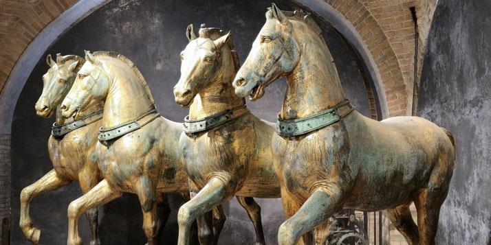A set of four ancient bronze horse sculptures with a golden patina, known as the Horses of Saint Mark.