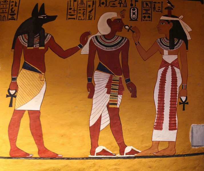 An ancient Egyptian tomb painting of the Opening of the Mouth ceremony. Anubis, a pharaoh, and a female figure hold ankhs, symbolizing the ritual for the deceased's afterlife journey.
