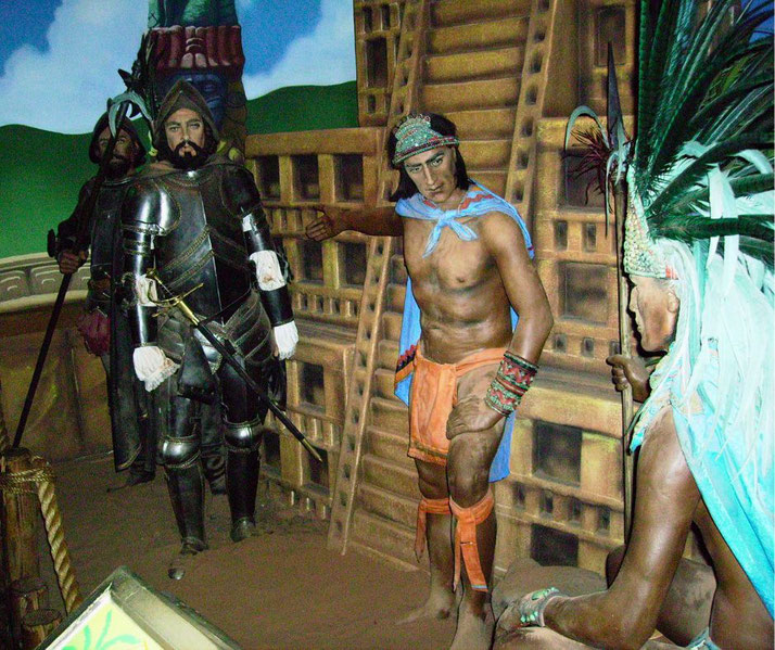 A historical diorama of Hernán Cortés meeting Aztec leaders. A Spanish conquistador in armor stands opposite Indigenous figures in traditional attire, with a pyramid in the background.