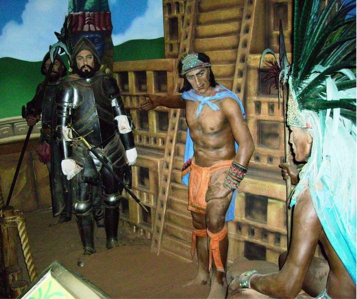 A historical diorama of Hernán Cortés meeting Aztec leaders. A Spanish conquistador in armor stands opposite Indigenous figures in traditional attire, with a pyramid in the background.