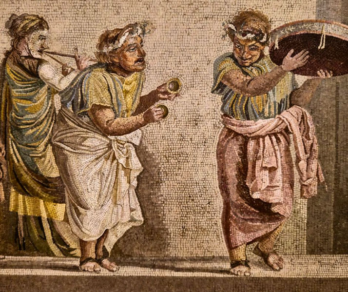 Ancient Roman mosaic of musicians playing cymbals, a tambourine, and a double pipe, dressed in colorful garments with theatrical masks and festive expressions.